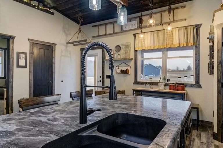 A kitchen worktop with an undermount sink and an arched industrial tap