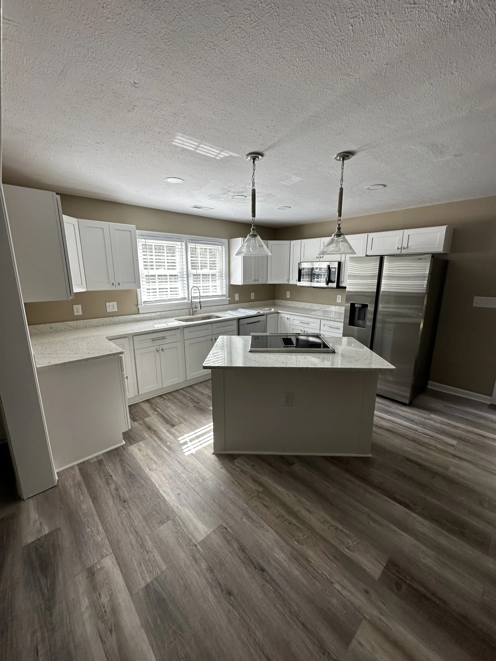 A finished kitchen with a large island and pendant lighting