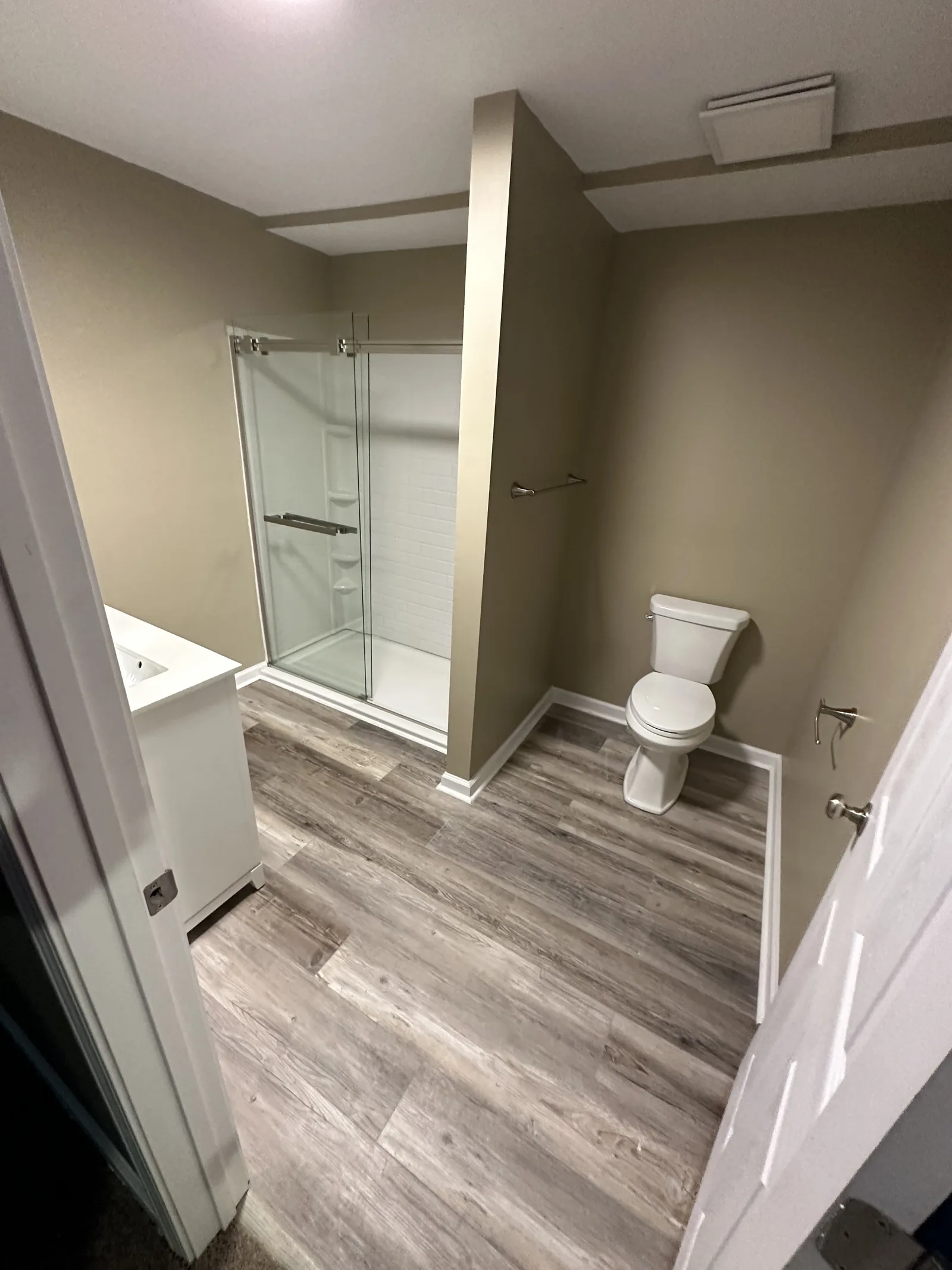A finished bathroom with a glass shower and wood-effect flooring