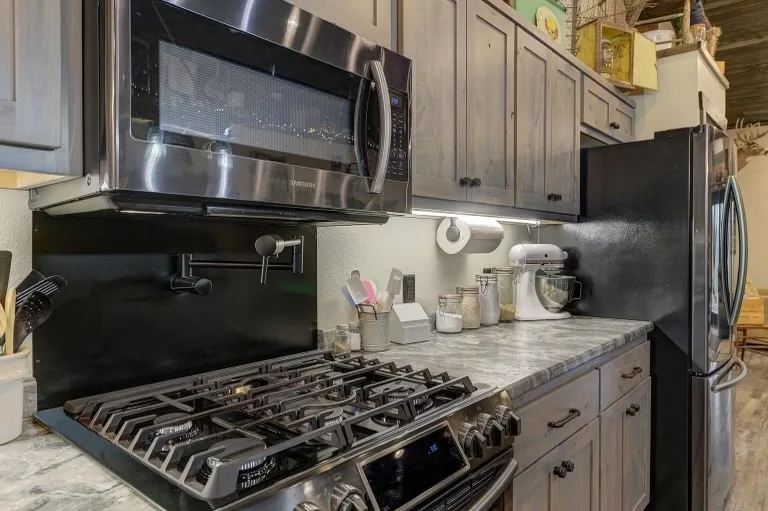 A stainless range and extractor hood set into grey shaker cabinetry