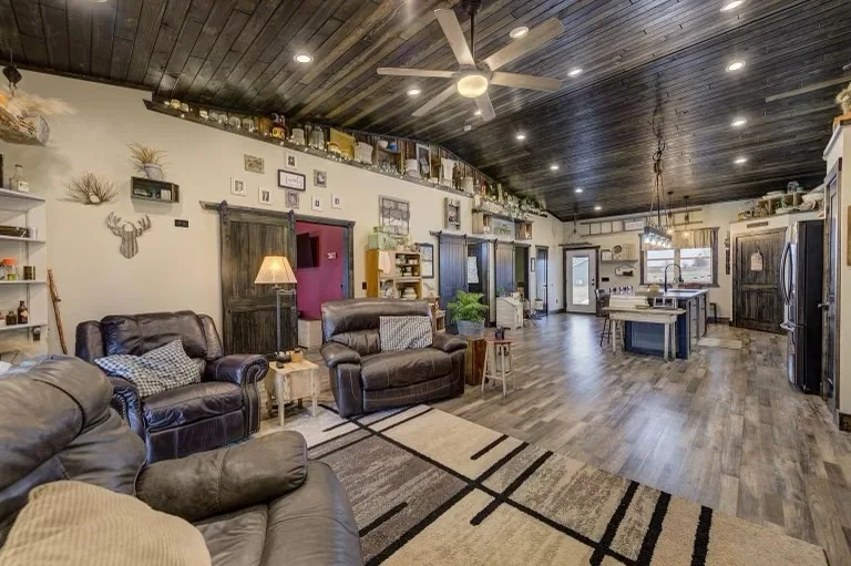 A long open-plan living room with wood-effect floors and a dark shiplap ceiling