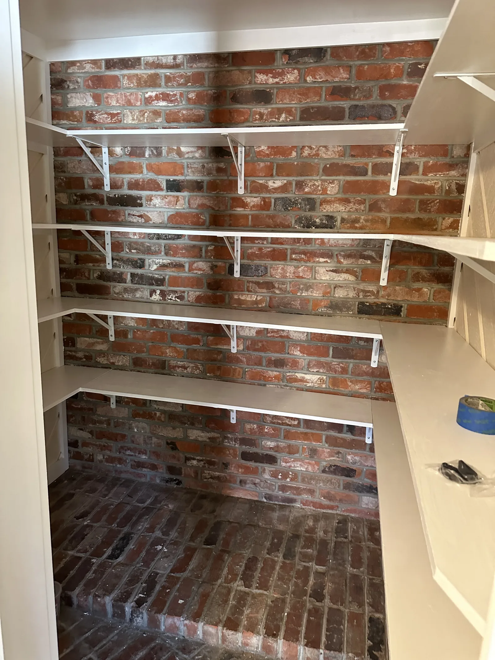 A brick-walled alcove fitted out with white shelving